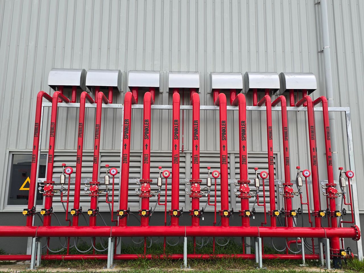 The Art of Drawing Readers In: Your attractive post title goes here Red industrial fire sprinkler pipes aligned on a factory exterior wall.